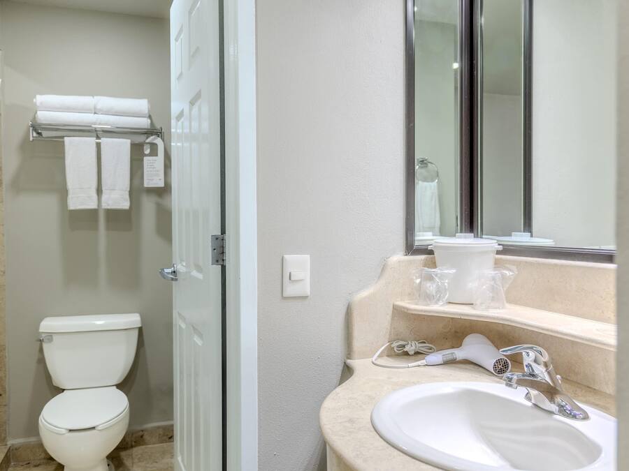 Un baño con inodoro, toallero, lavamanos y espejo.