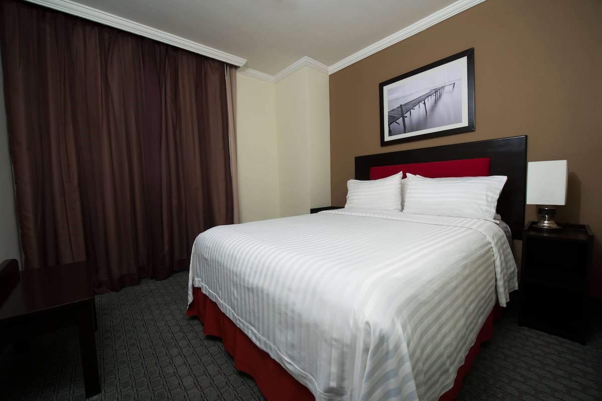 A hotel room with a large bed, a desk, and a chair.