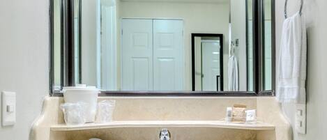 A bathroom with a sink, mirror, and a towel rack.