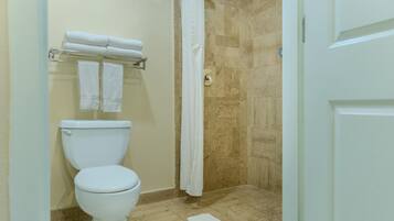 A bathroom with a toilet, a towel rack, a shower curtain, and a tiled floor.