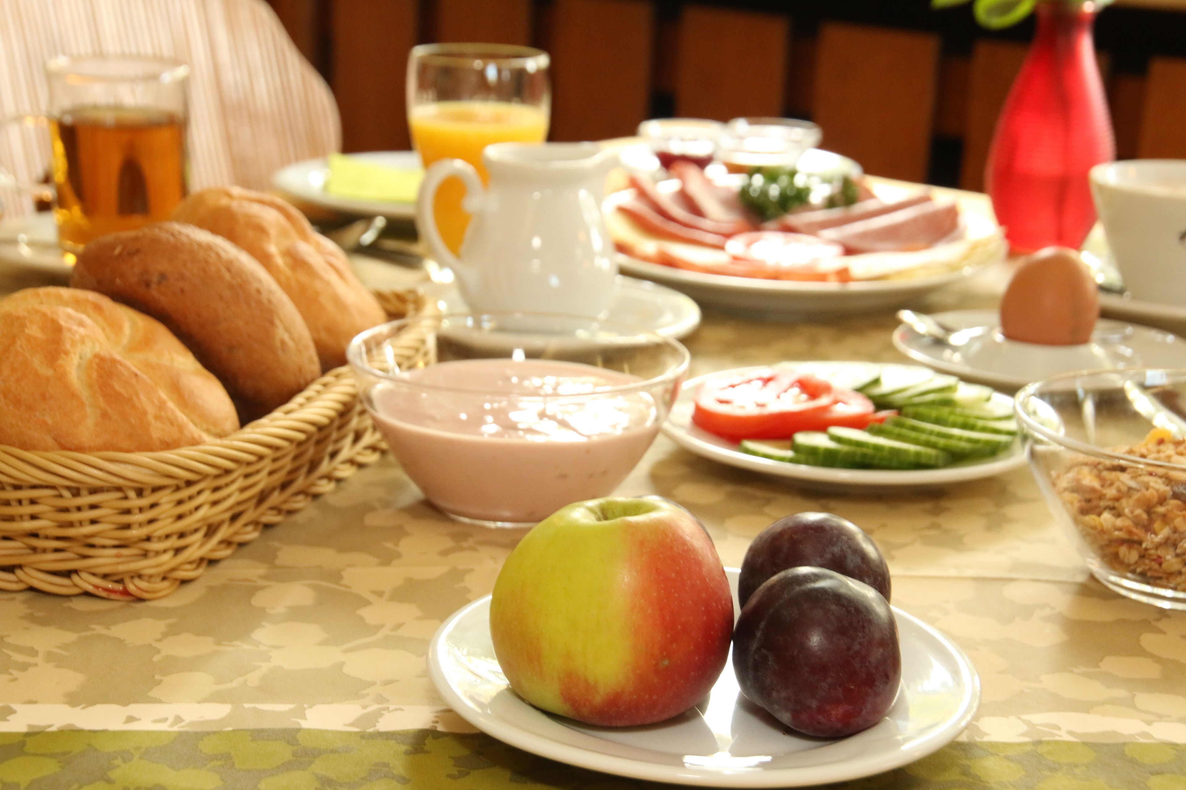 Ein Frühstückstisch mit Brot, Obst, Gemüse und einem Saftkrug.