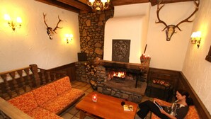 Una sala de estar acogedora con chimenea de piedra, mobiliario de madera y decoración de cornamenta.