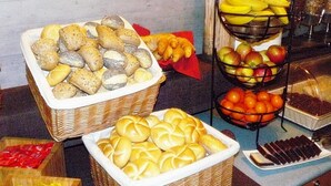 A buffet with various baked goods, fruits, and condiments.