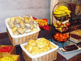 A buffet with various baked goods, fruits, and condiments.