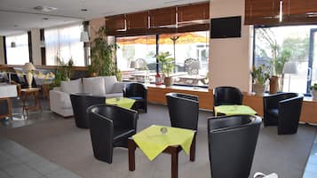 A hotel lobby with seating areas, a reception desk, and large windows with views.