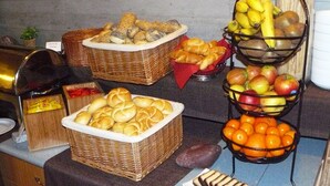 Una mesa de buffet con diversos alimentos, incluyendo pan, frutas y pastelería.