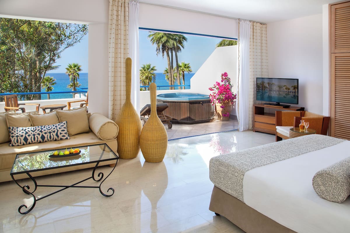 Una habitación de hotel moderna con balcón, sofá, televisión y una cama grande.