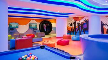 Relax and socialize in our vibrant recreational area, featuring a pool table, comfortable seating, and artwork.