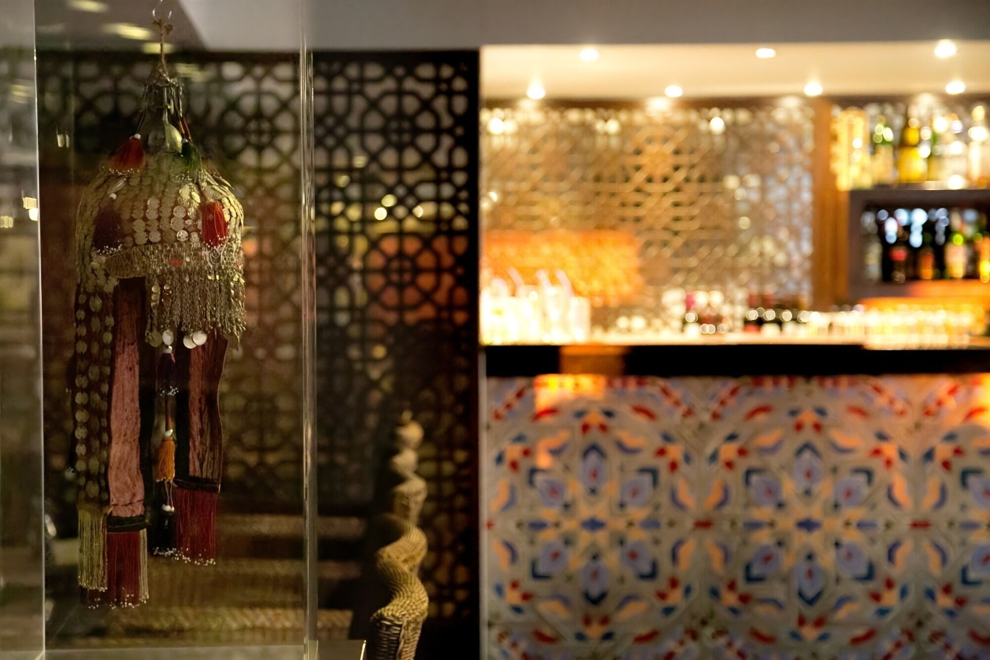 Un espace bar agrémenté d’un mur à motifs et d’une vitrine où sont exposés des objets décoratifs.