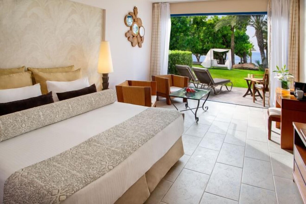 Una habitación de hotel con una cama grande, un escritorio y vistas al exterior.
