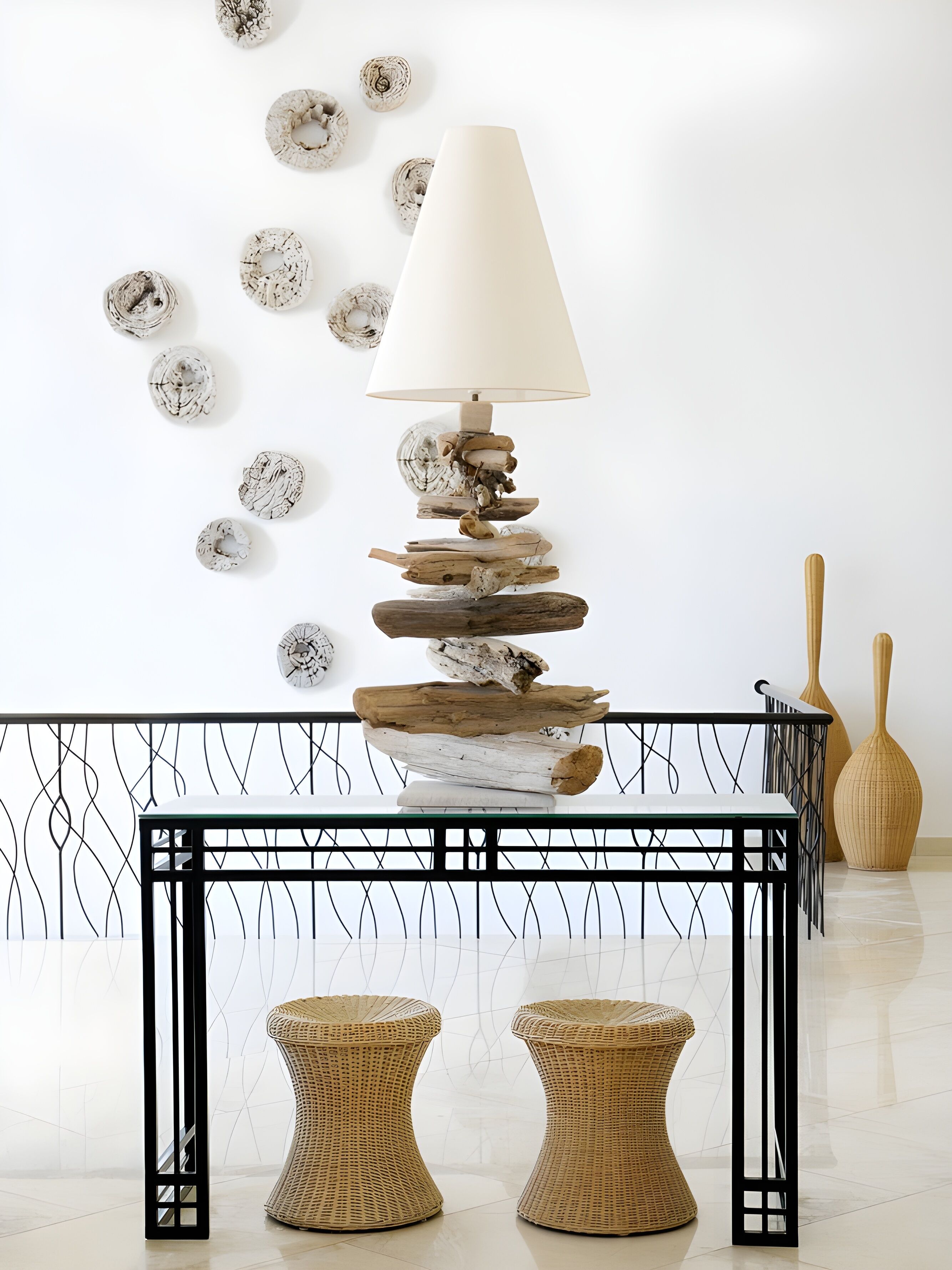 A modern interior with a unique lamp, wicker stools, and decorative plates on the wall.