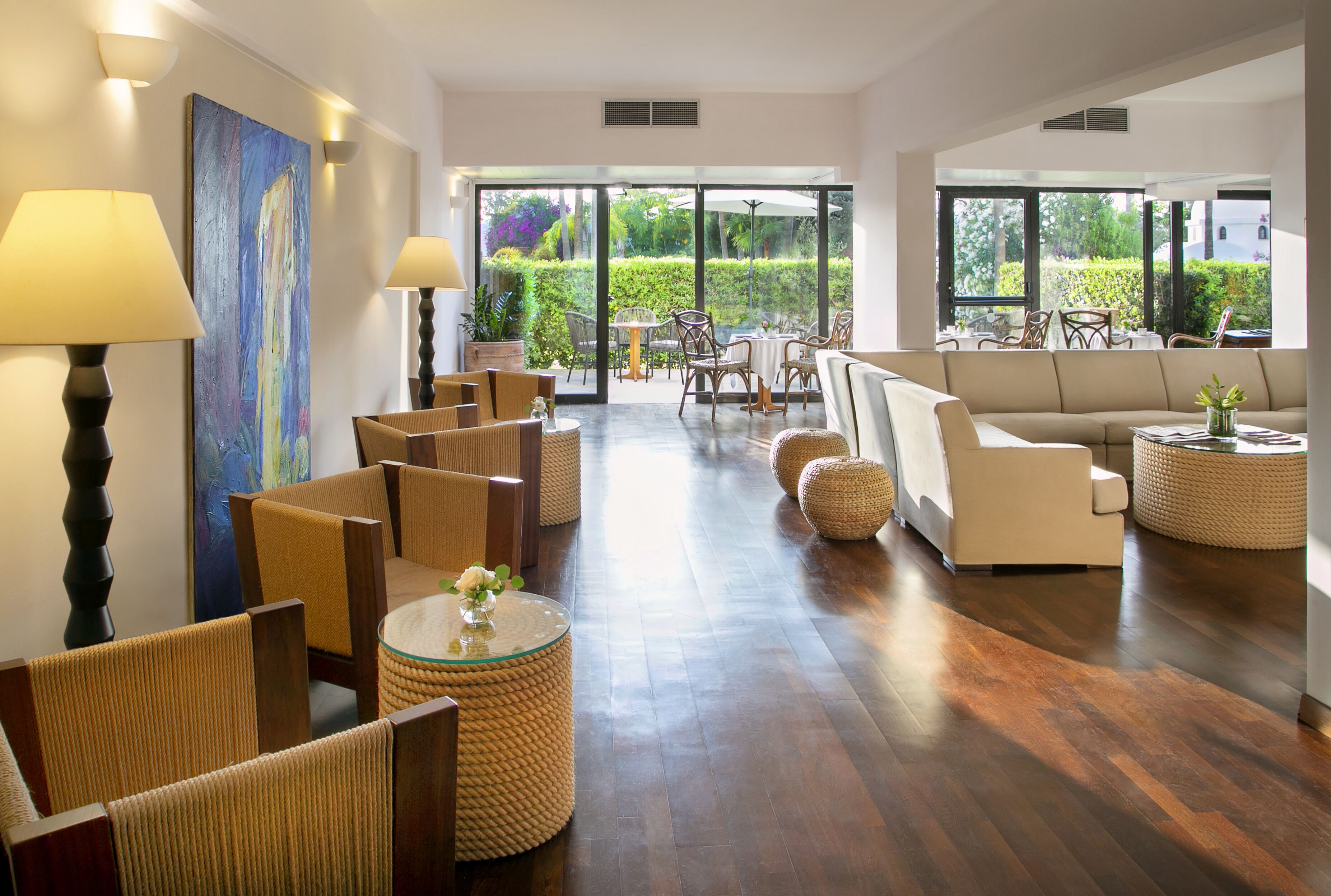 A spacious living area with a sofa, chairs, a coffee table, and a painting on the wall.