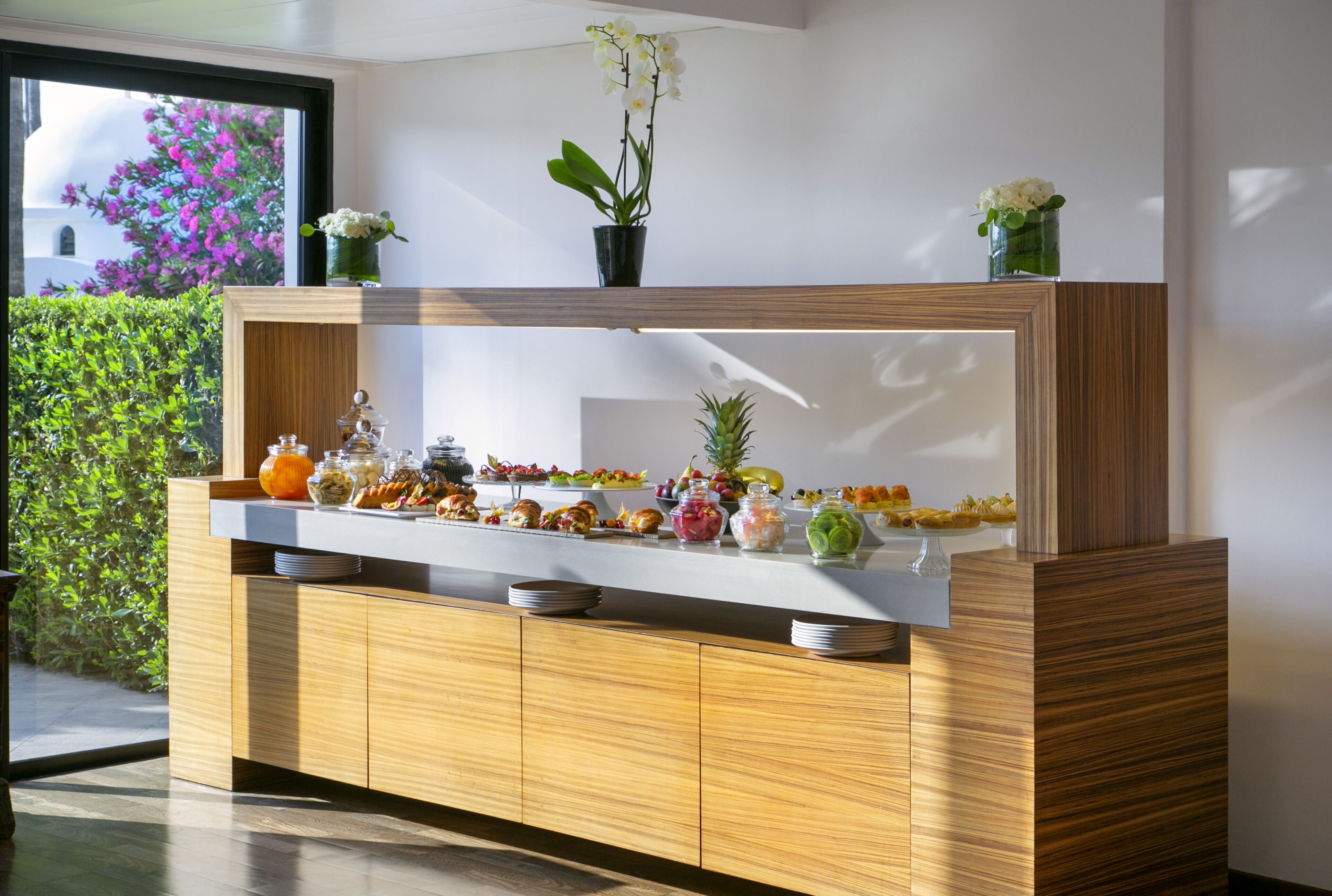 A buffet setup with various food items and decorative plants.