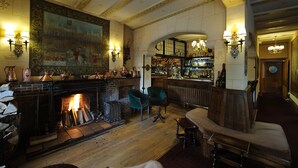 A bar area with a fireplace, seating, and a bar stocked with bottles.