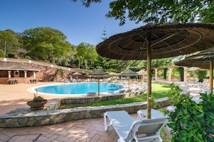 Una piscina al aire libre, sombrillas, sillones reclinables de piscina