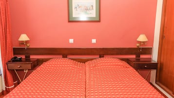 A hotel room with a double bed, two bedside tables with lamps, a wooden headboard, and a framed picture on the wall.