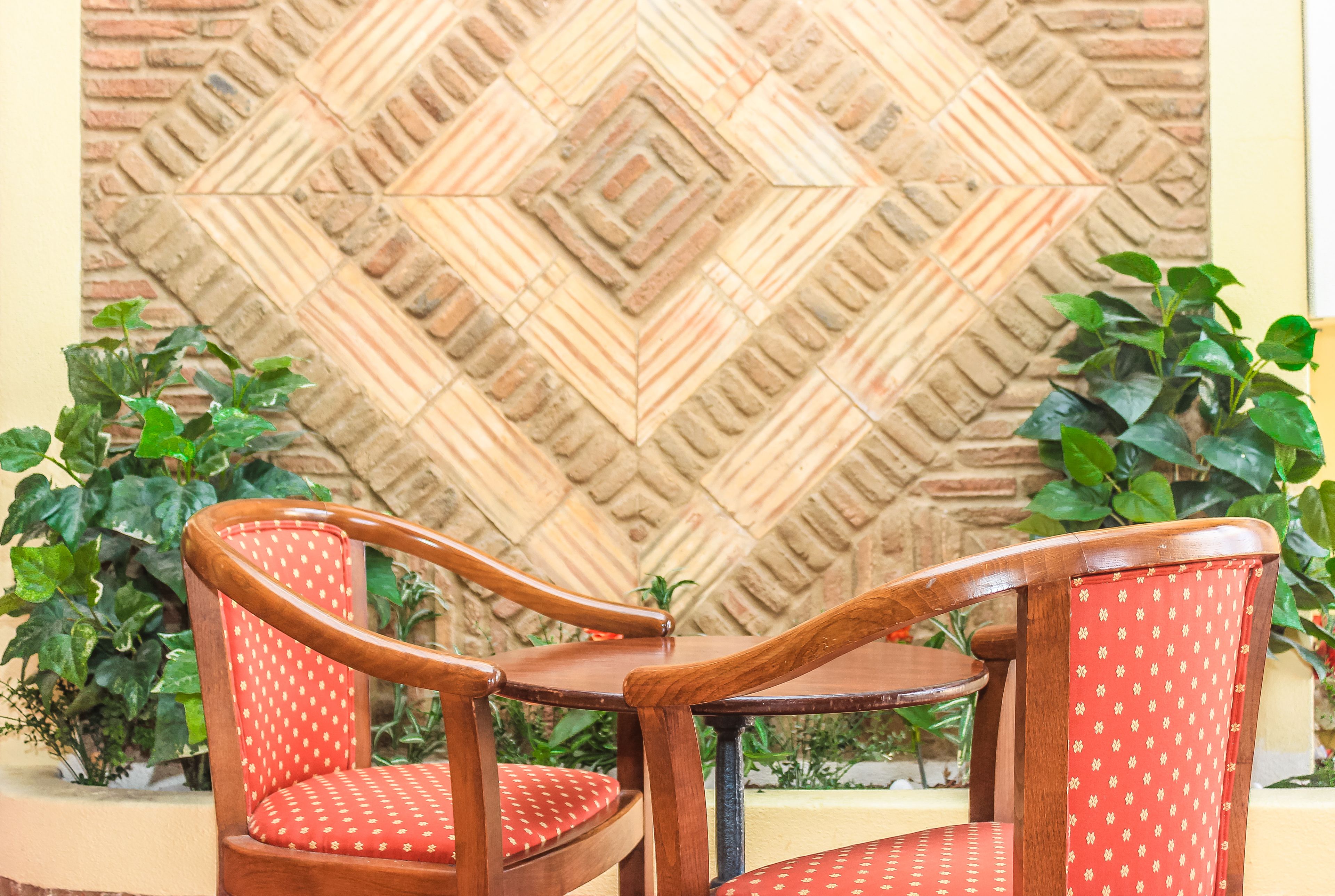 A wooden chair with a red cushion and a table in front of a decorative wall.