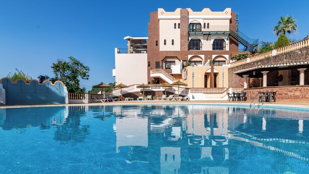 Et hotel med swimmingpool, en bygning over flere etager, og en trappe op til de øvre niveauer.