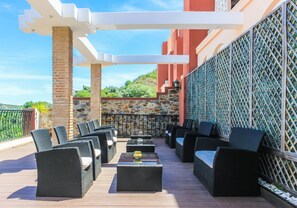 An outdoor patio with wicker furniture and a stone wall backdrop. - Hotel Colina Dos Mouros (Silves)