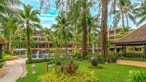 Un resort con piscina, palmeras y un jardín bien cuidado.