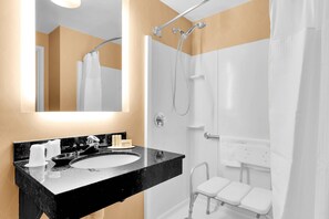 Een moderne badkamer met een zwart marmeren wastafel, een grote spiegel, een douche met glazen deur en een witte handdoekhouder.