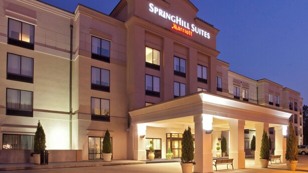 Un hotel con fachada moderna, un letrero destacado de SpringHill Suites Marriott y un área de entrada cubierta con asientos.