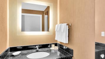 A modern bathroom with a large mirror, a sink, and a towel rack.