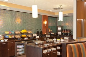 Montaje de bufé con diversos alimentos, una estación de café y una zona de estar.