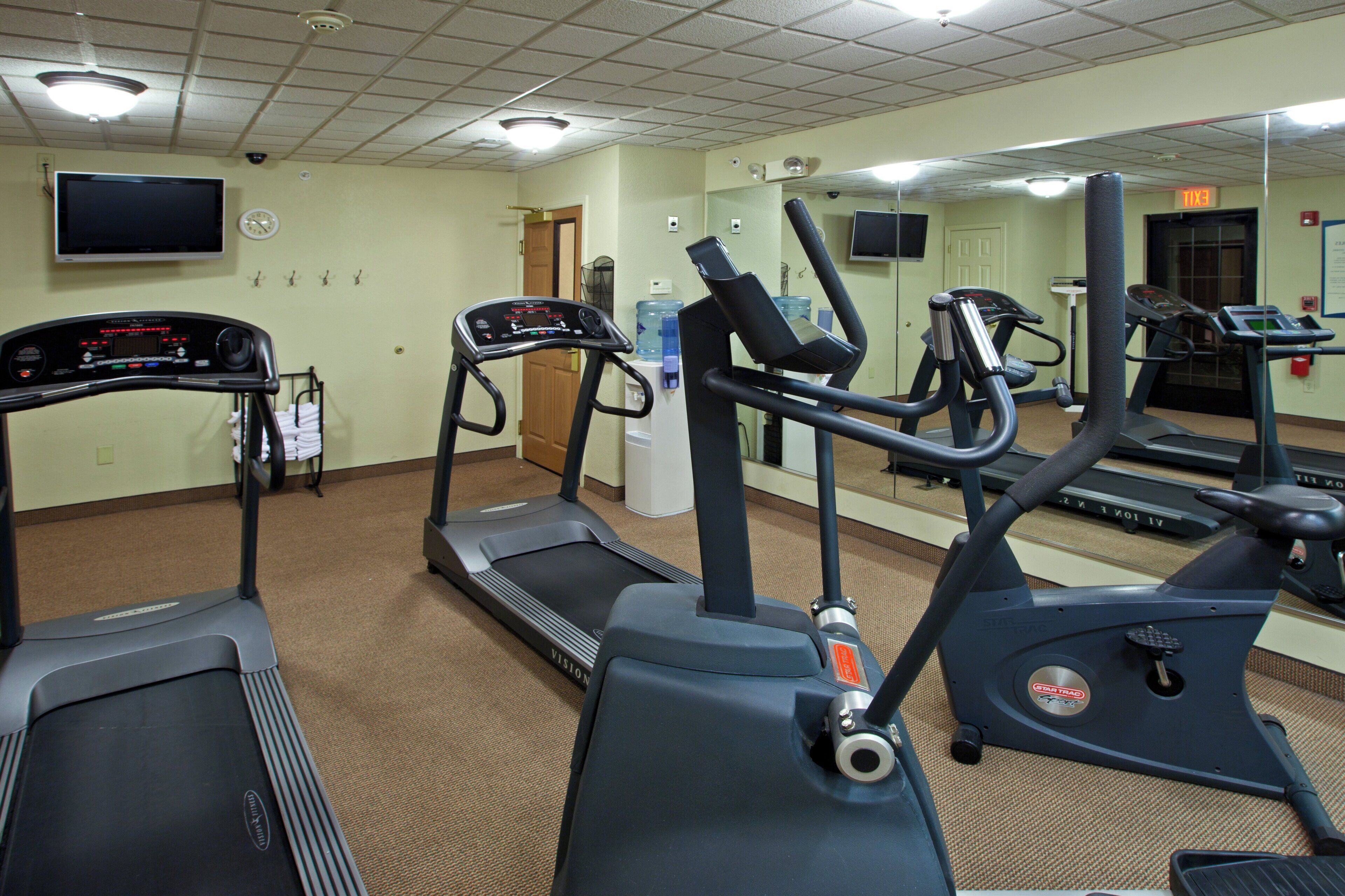 A gym with treadmills, elliptical machines, and a water dispenser.