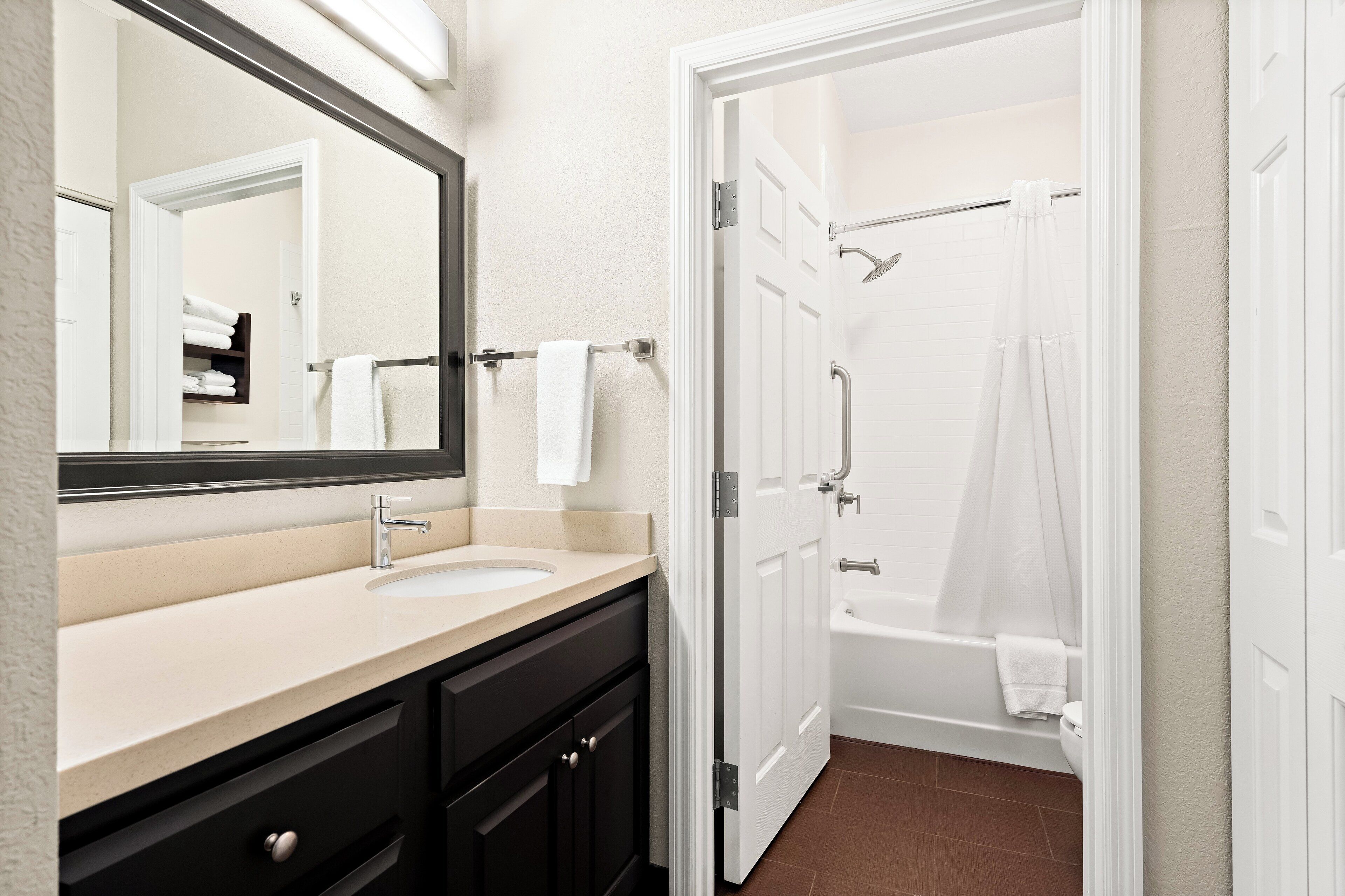 A bathroom with a sink, mirror, and a shower area.