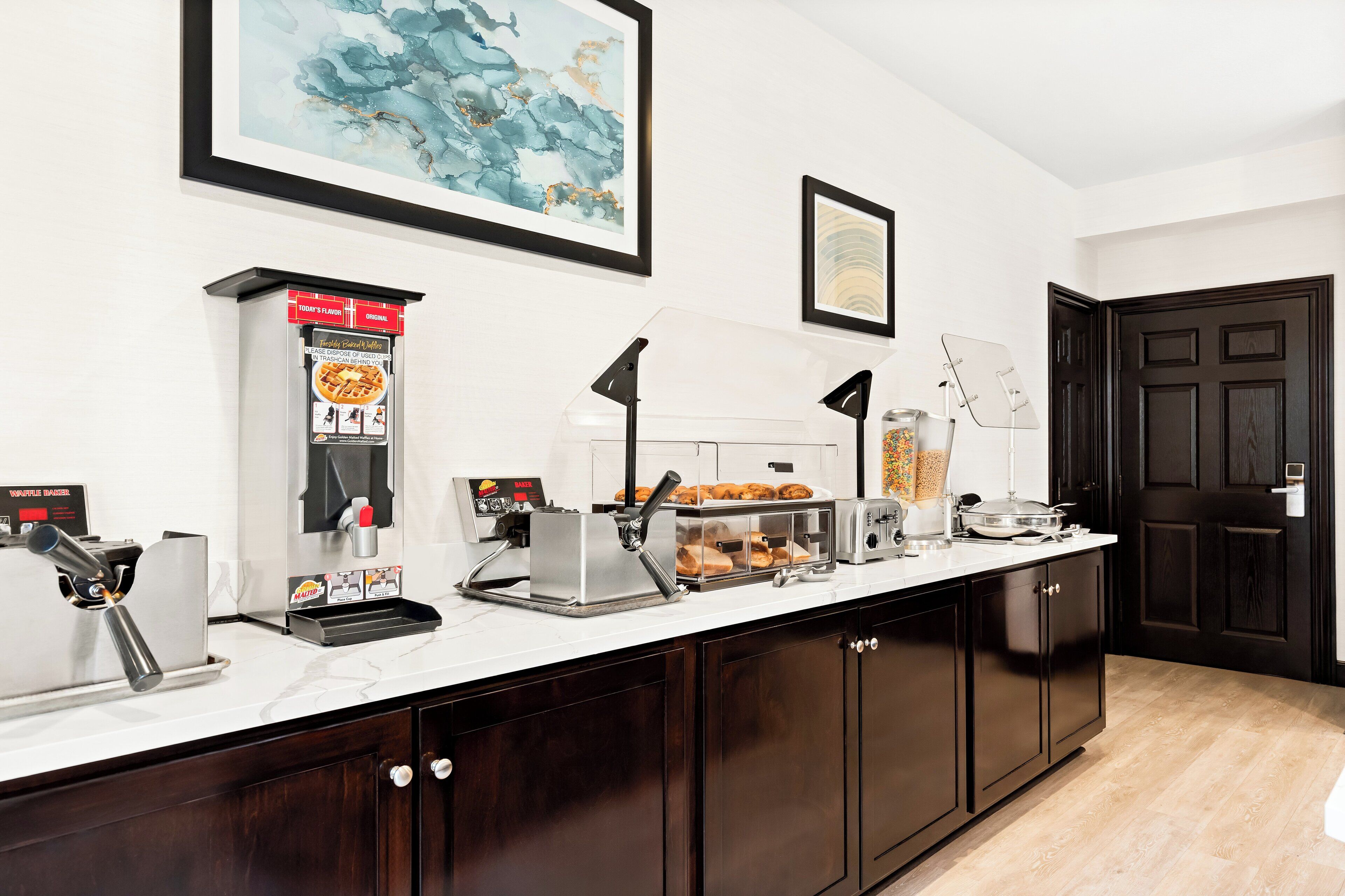 A kitchen area with a coffee machine, toaster, and a food display.