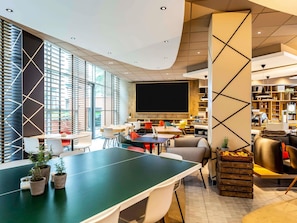 Une salle de conférence moderne équipée d’une grande table, de chaises, d’un écran de projection et d’une bibliothèque.