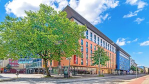 Un hôtel à la façade moderne, avec de nombreux étages et une palette de couleurs dominante composée de rouge et de bleu.