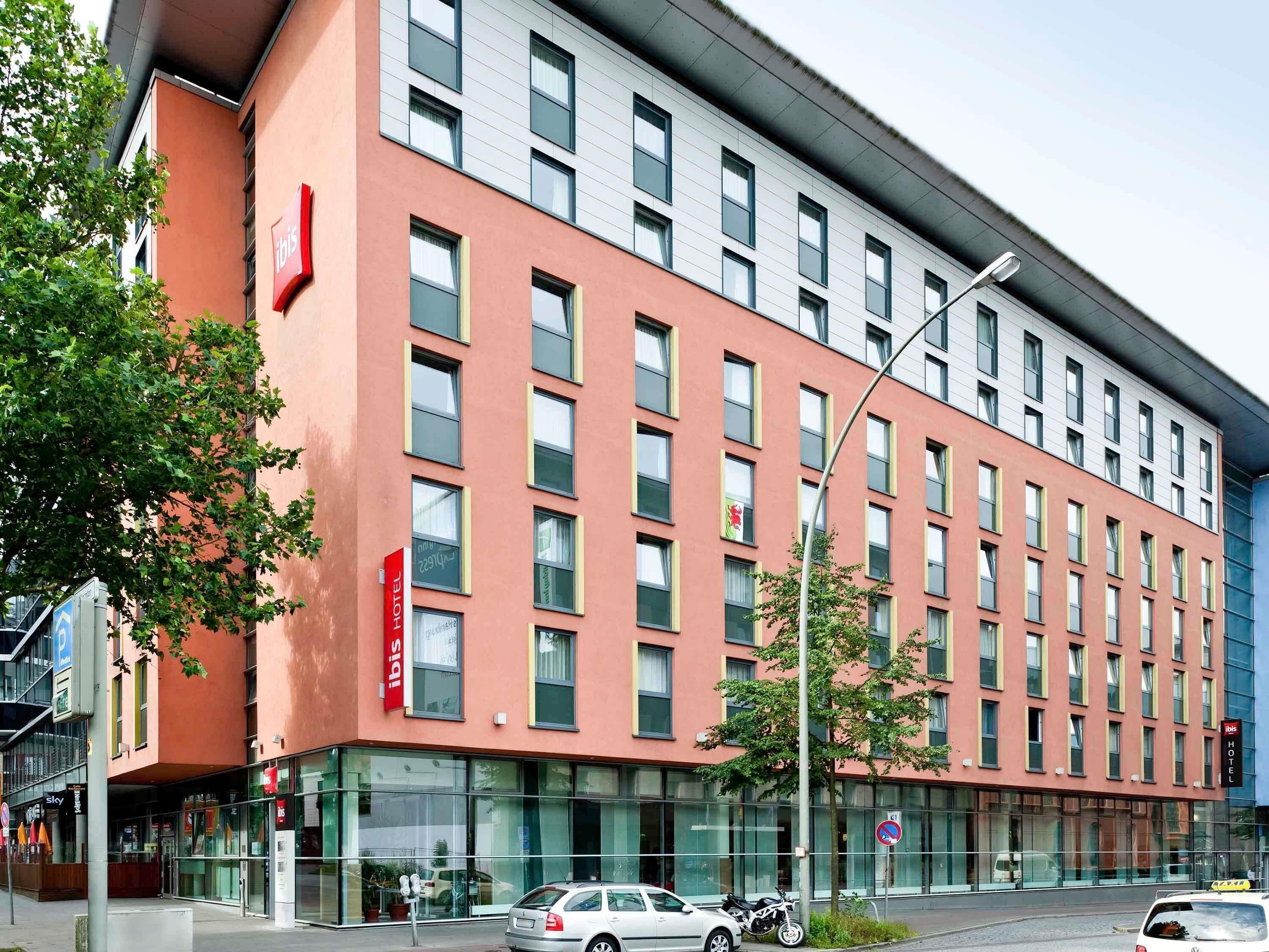A modern hotel building with multiple floors, large windows, and a prominent red and white color scheme.