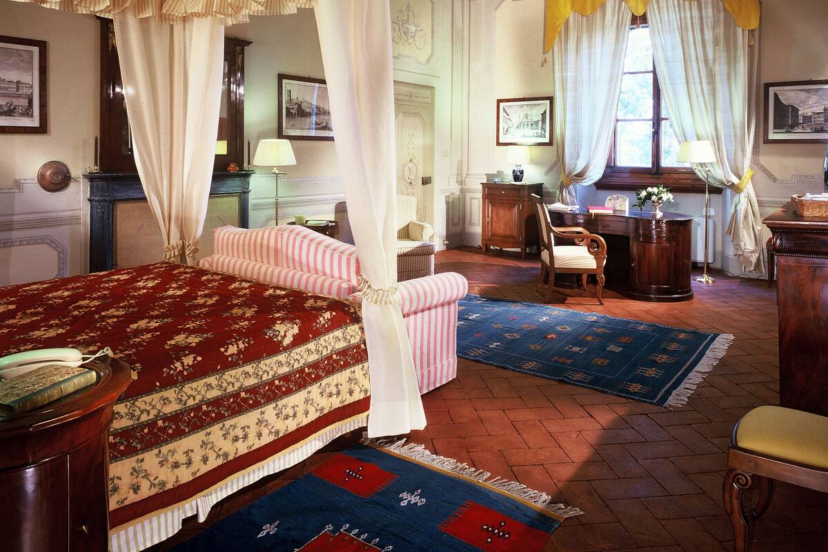 A traditional bedroom with a four-poster bed, a desk, and a chair.
