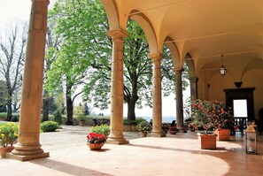 Un espacio al aire libre cubierto con columnas, plantas en macetas y vistas al mar.