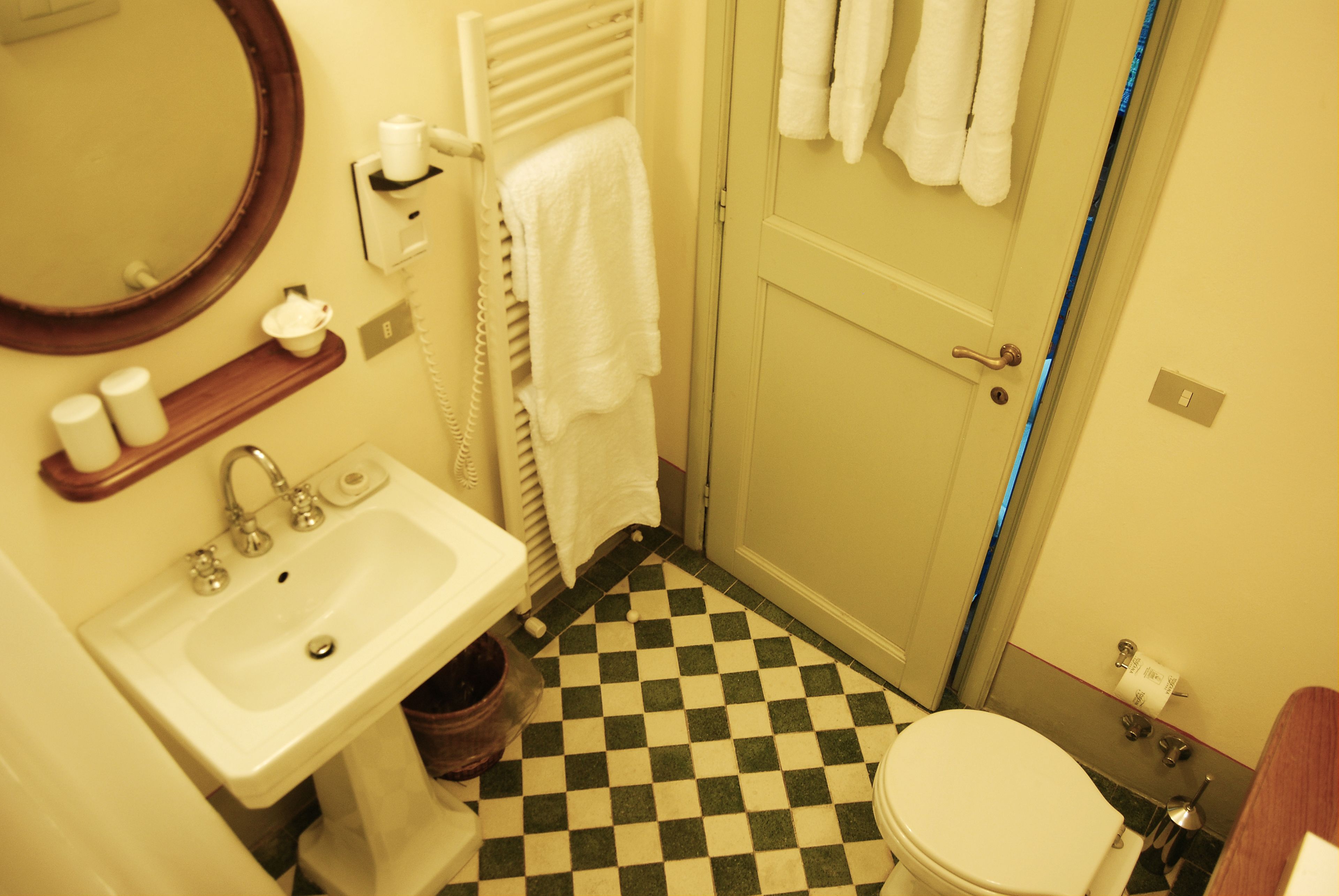 A bathroom with a checkered floor, a sink, a toilet, a mirror, and a towel rack.