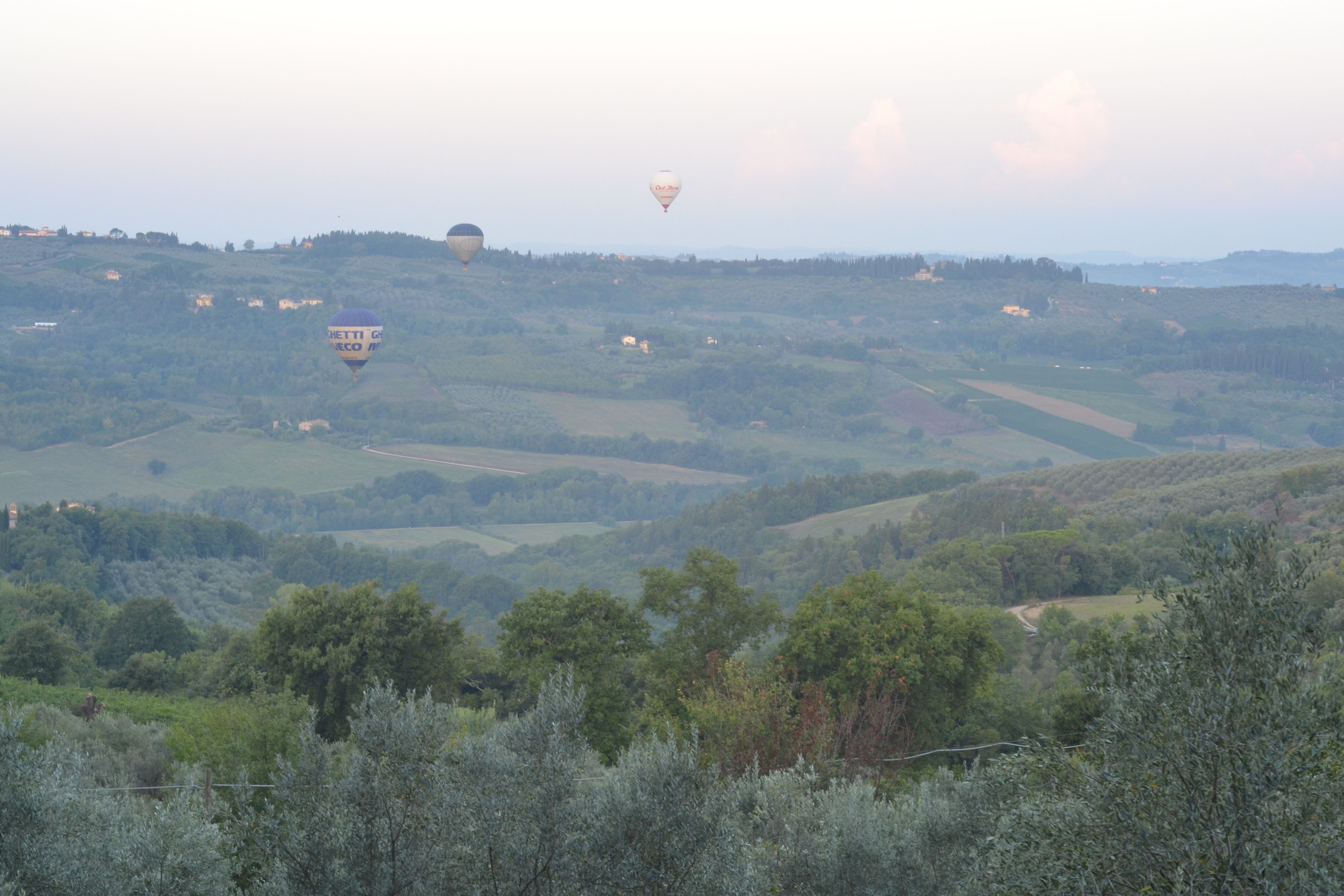 A rural landscape with rolling hills and scattered buildings.