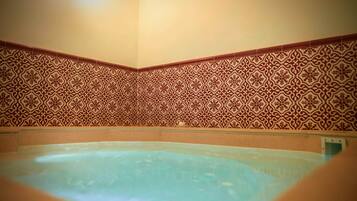 Relax in a spacious room with a large hot tub against a geometric-patterned wall.
