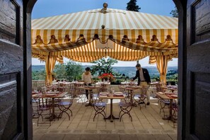 Un espace de restauration en plein air avec des tables et des chaises, un auvent à rayures et une vue sur le paysage.