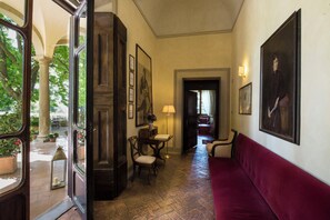 Un couloir avec un canapé rouge, une porte en bois et un portrait encadré accroché au mur.