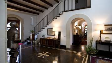 A spacious lobby with a polished marble floor, a grand staircase, and a statue of a knight.