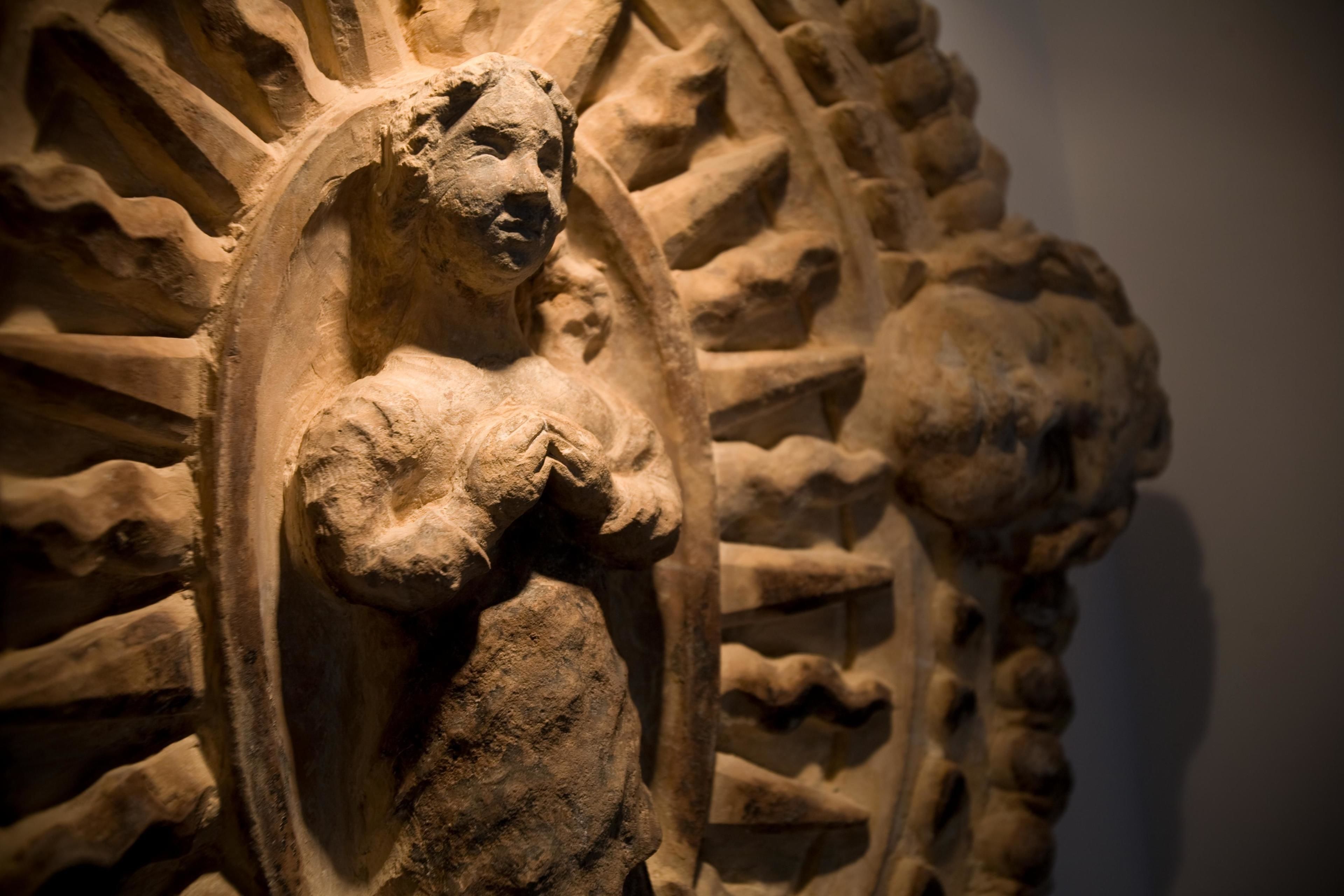 A stone carving of a figure with a halo, surrounded by intricate patterns.