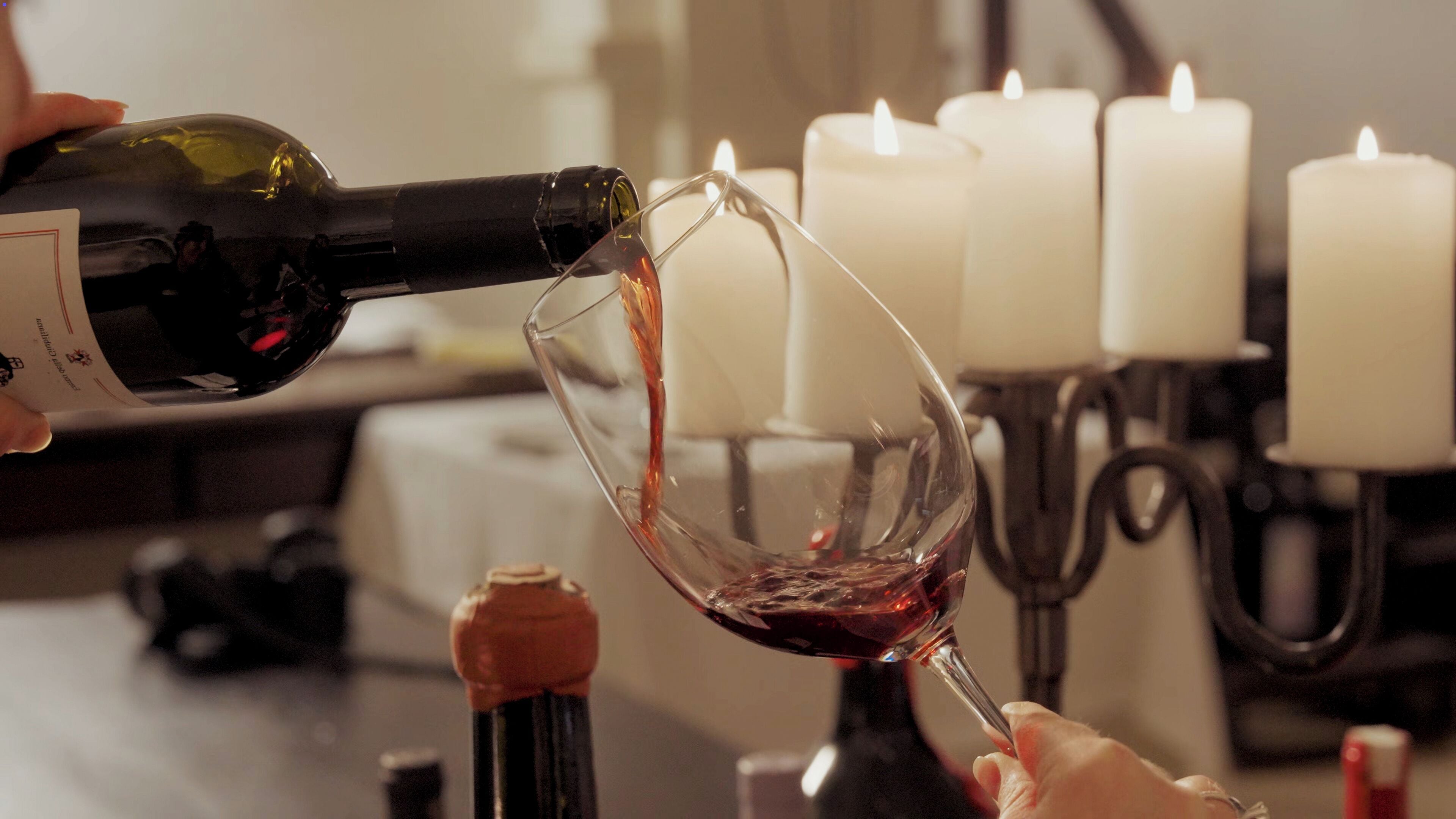 A bottle of red wine being poured into a glass.