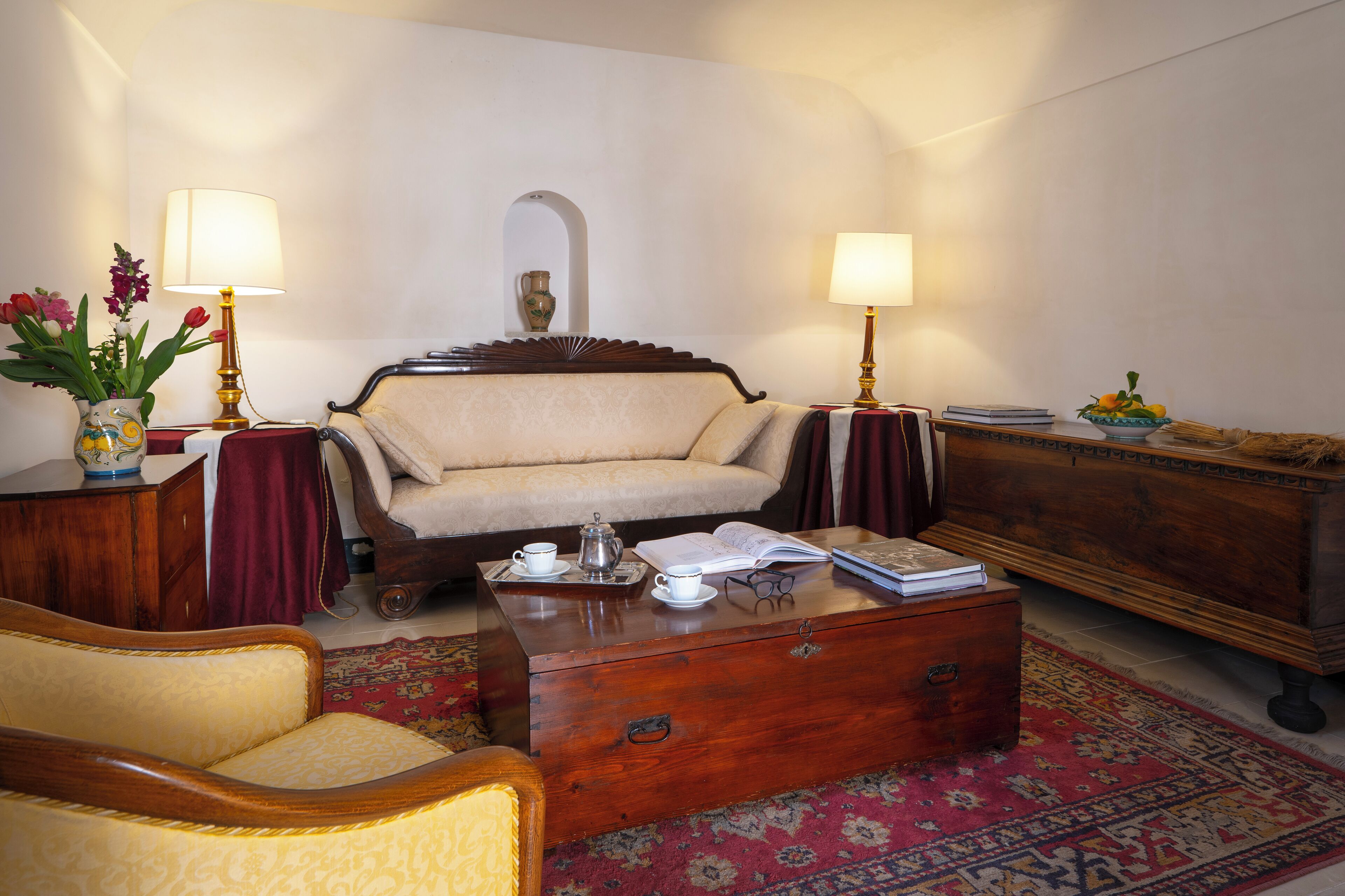 A cozy living room with a sofa, a wooden coffee table, a side table with a lamp, and a decorative vase.