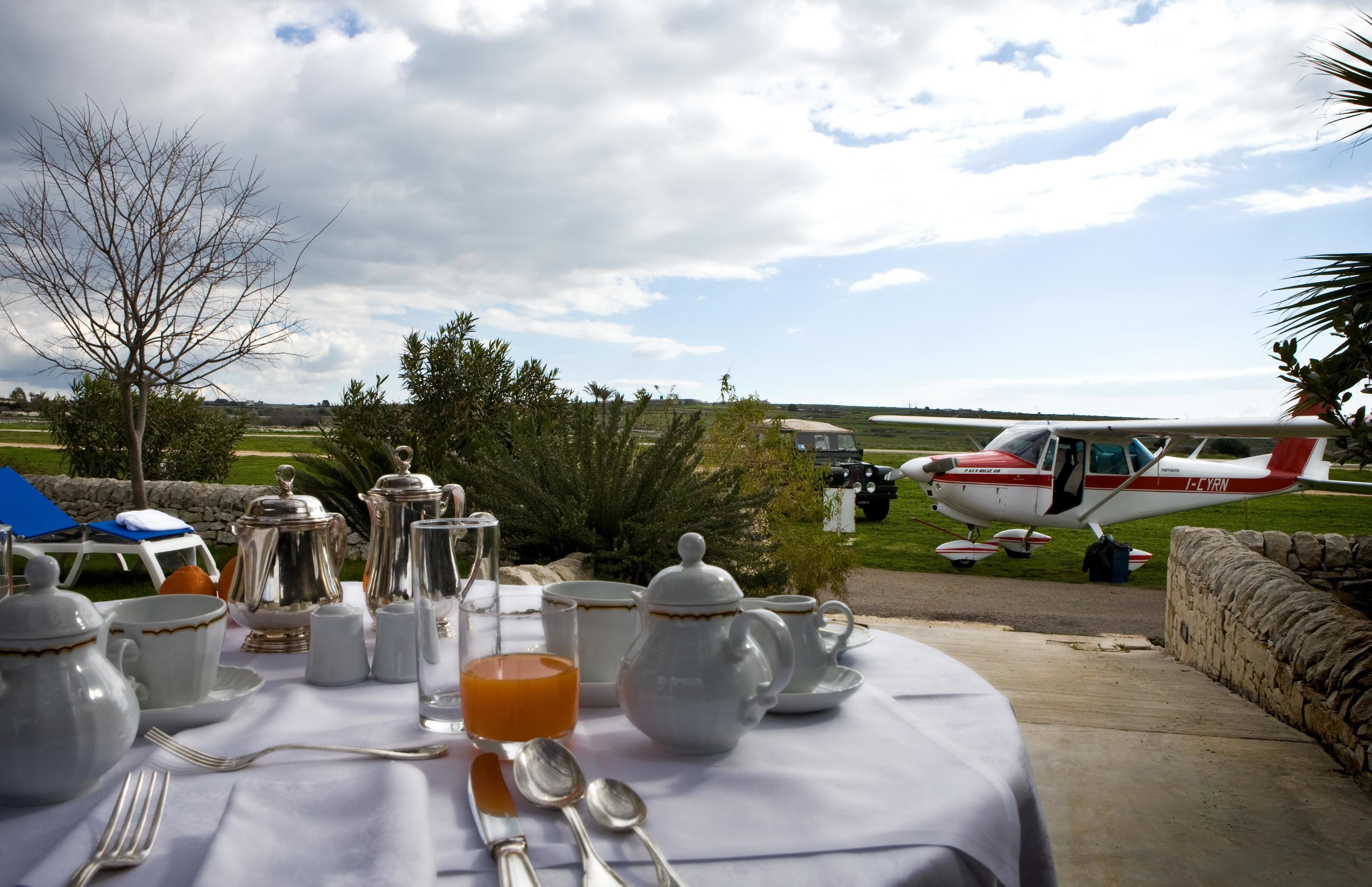 A table set for breakfast with a view of a small airplane in the background.