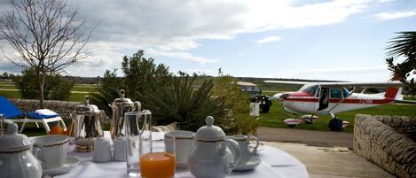 A table set for breakfast with a view of a small airplane in the background.