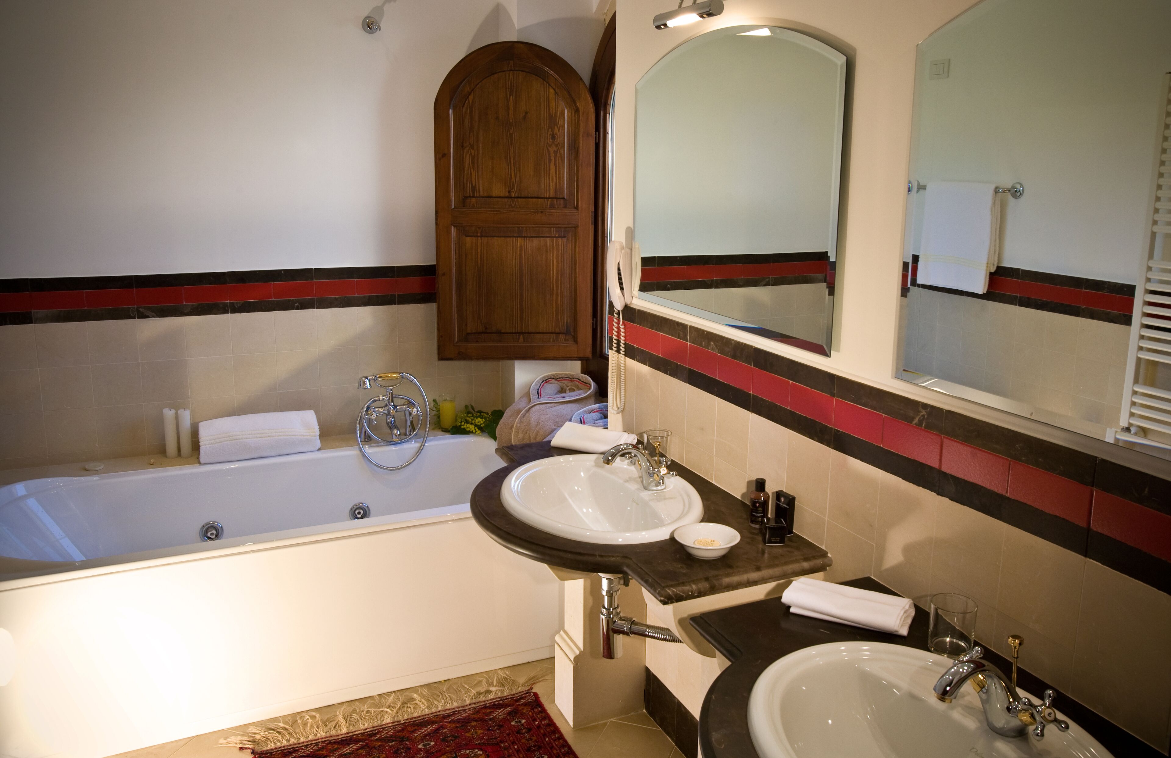 A bathroom with a bathtub, two sinks, a wooden cabinet, and a mirror.