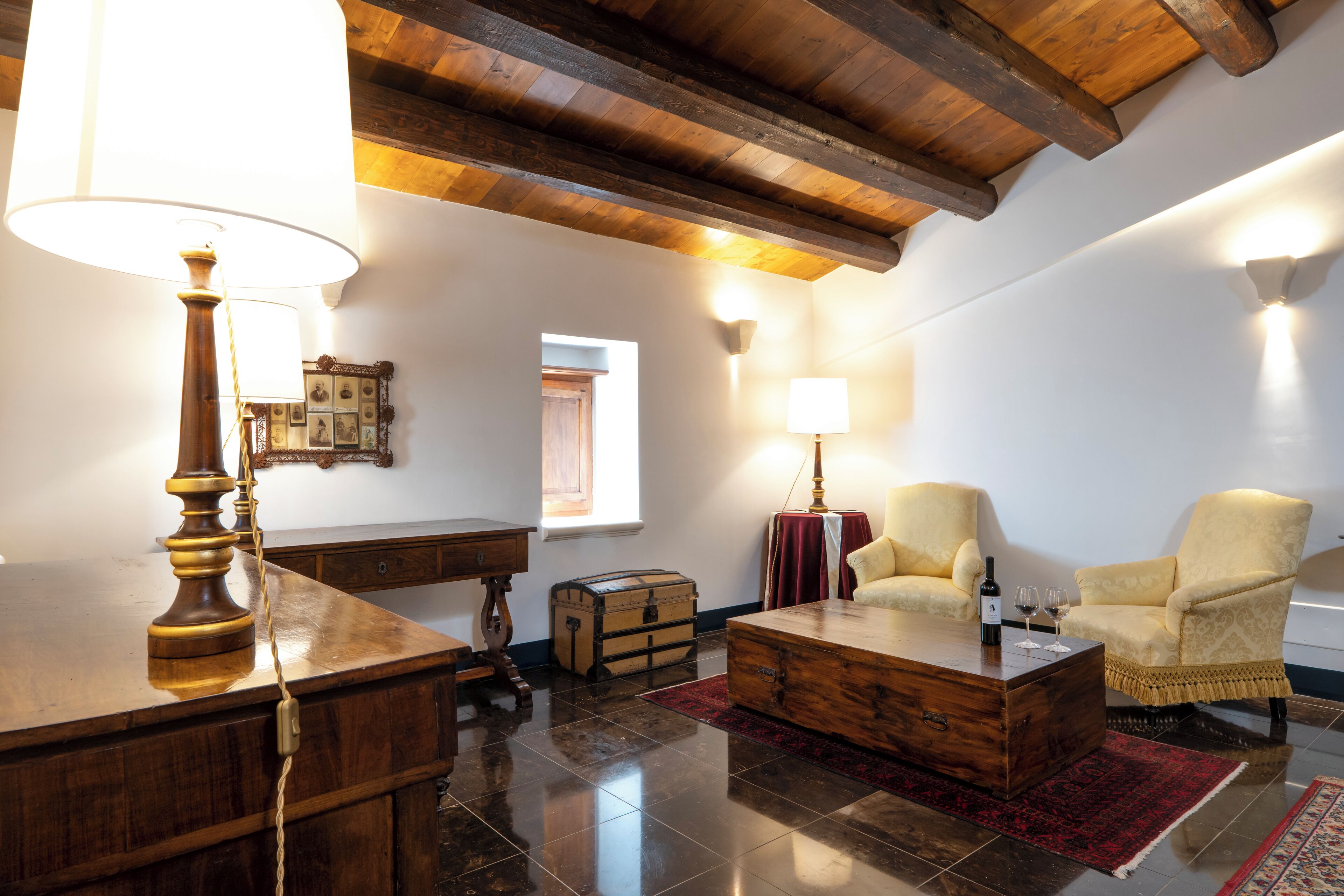 A cozy living room with wooden furniture, a red rug, and a wooden ceiling.
