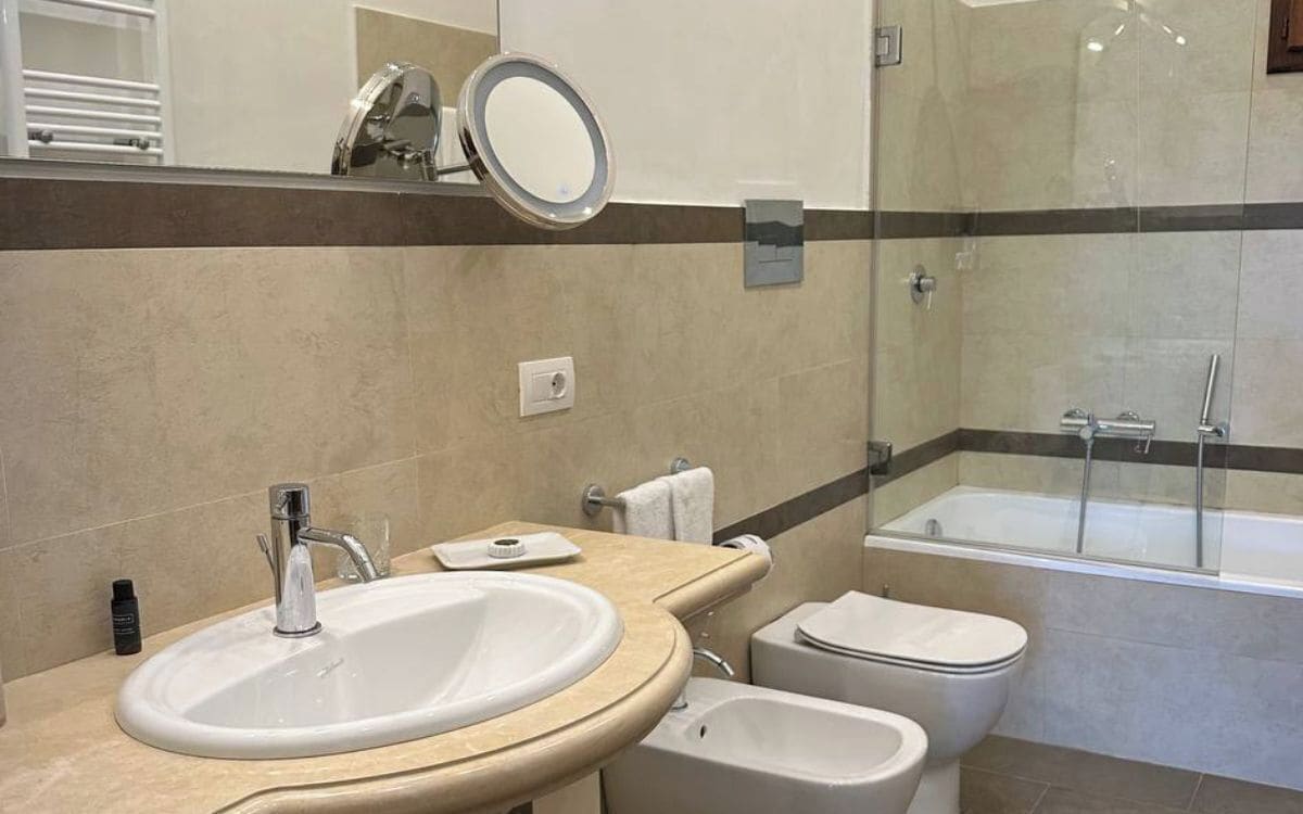 A modern bathroom with a large sink, a bidet, a toilet, and a glass-enclosed shower.